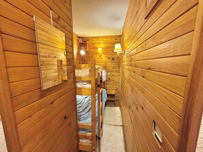 Ein schmaler Gang mit Holzwänden, einem Etagenbett und zwei Wandlampen.