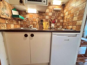 A compact kitchen with a white refrigerator, a microwave above the sink, and a tiled backsplash. - Ground floor, terrace, tv, ski locker, 26m², Praz sur Arly (Praz-sur-Arly)