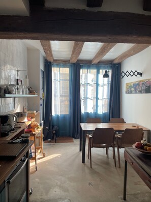 A rustic kitchen with wooden beams, a dining table, chairs, and a dog. - Cottage 'Les Maisons De Malo' with shared terrace and Wi-Fi (Beaulieu-lès-Loches)