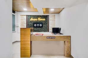 Bancada de recepção com uma placa que diz 'Arusai Homes OYO' e a etiqueta 'RECEPÇÃO'.