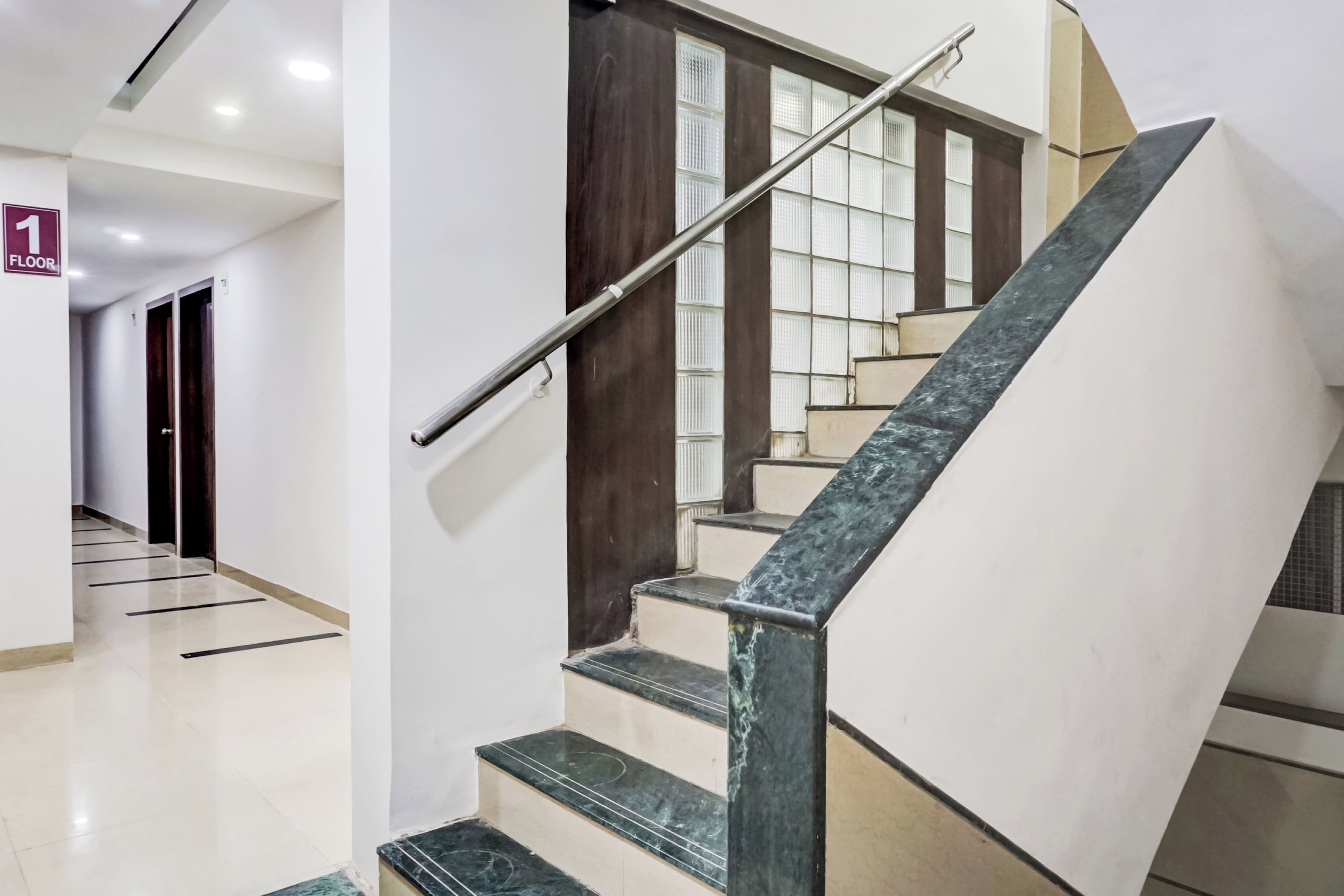 A modern staircase with a metal handrail, a wooden door, and a glass window.