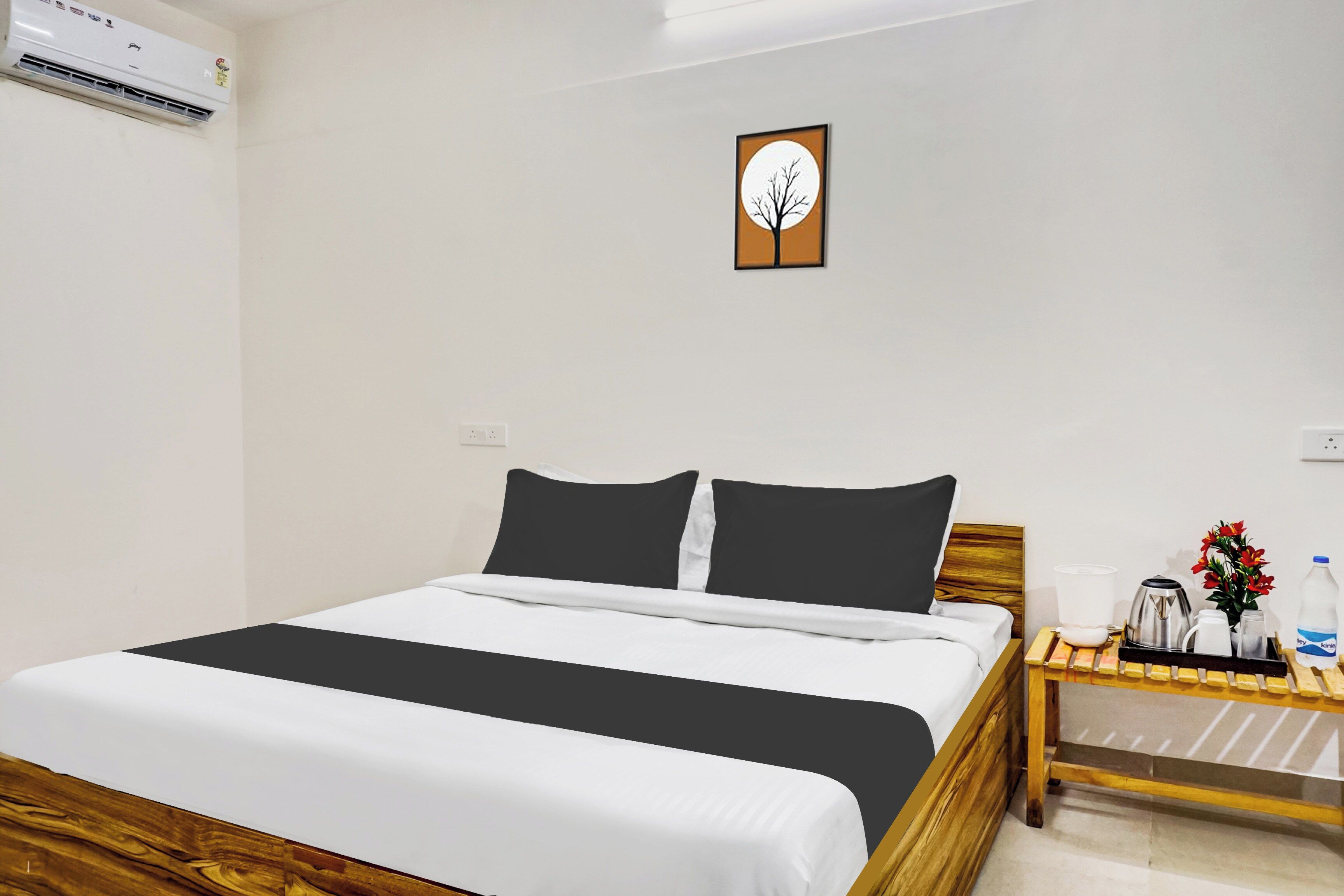 A hotel room with a bed, bedside table, and a wall-mounted air conditioner.