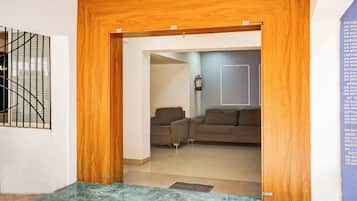 Una habitación con una puerta de madera que da a una sala de estar con dos sofás y un extintor en la pared.