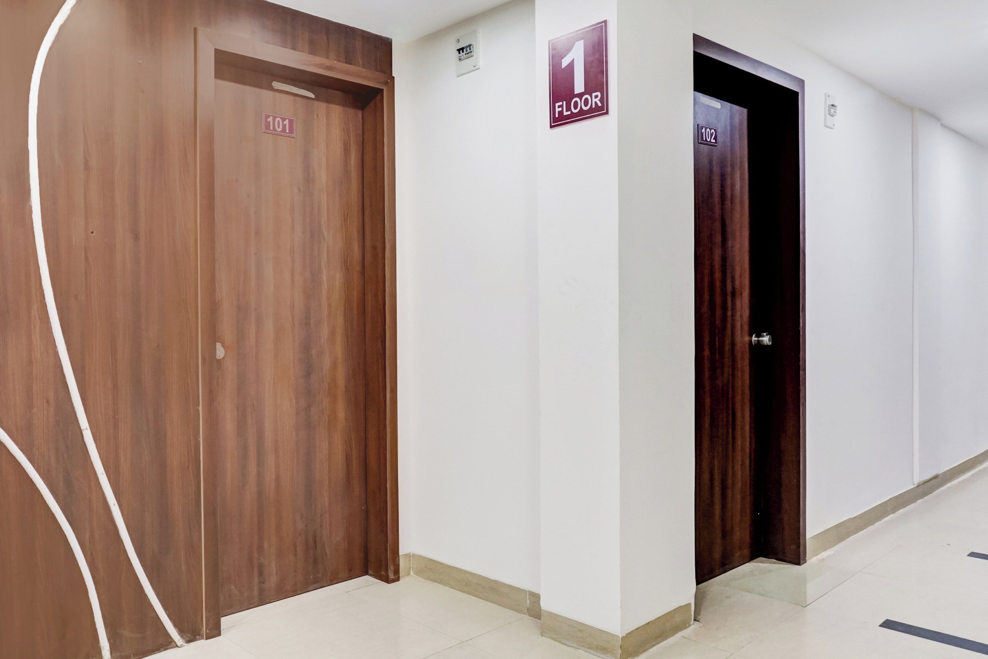 A hallway with wooden doors, a sign indicating the first floor, and a door labeled 102.