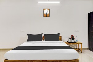 A hotel room with a bed, a bedside table with a lamp, and a wall-mounted artwork.