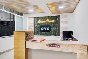 A reception desk with a sign reading 'Arusai Homes OYO' and a 'RECEPTION' label.