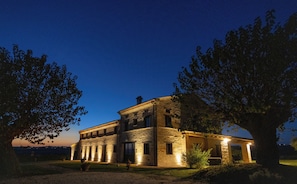A two-story stone building with a flat roof, large windows, and a well-lit entrance. - "Villa Vernaschi – Heart of Le Marche" (Marche)