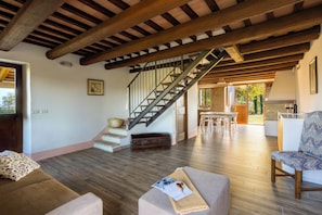 A spacious living area with a wooden staircase, a dining table, and a comfortable seating area. - "Villa Vernaschi – Heart of Le Marche" (Marche)