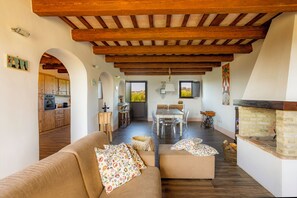 A spacious living area with a wooden ceiling, a dining table with chairs, a fireplace, and a kitchen visible through an archway. - "Villa Vernaschi – Heart of Le Marche" (Marche)
