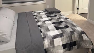 A bedroom with a bed, a window with blinds, a door, and a carpeted floor.