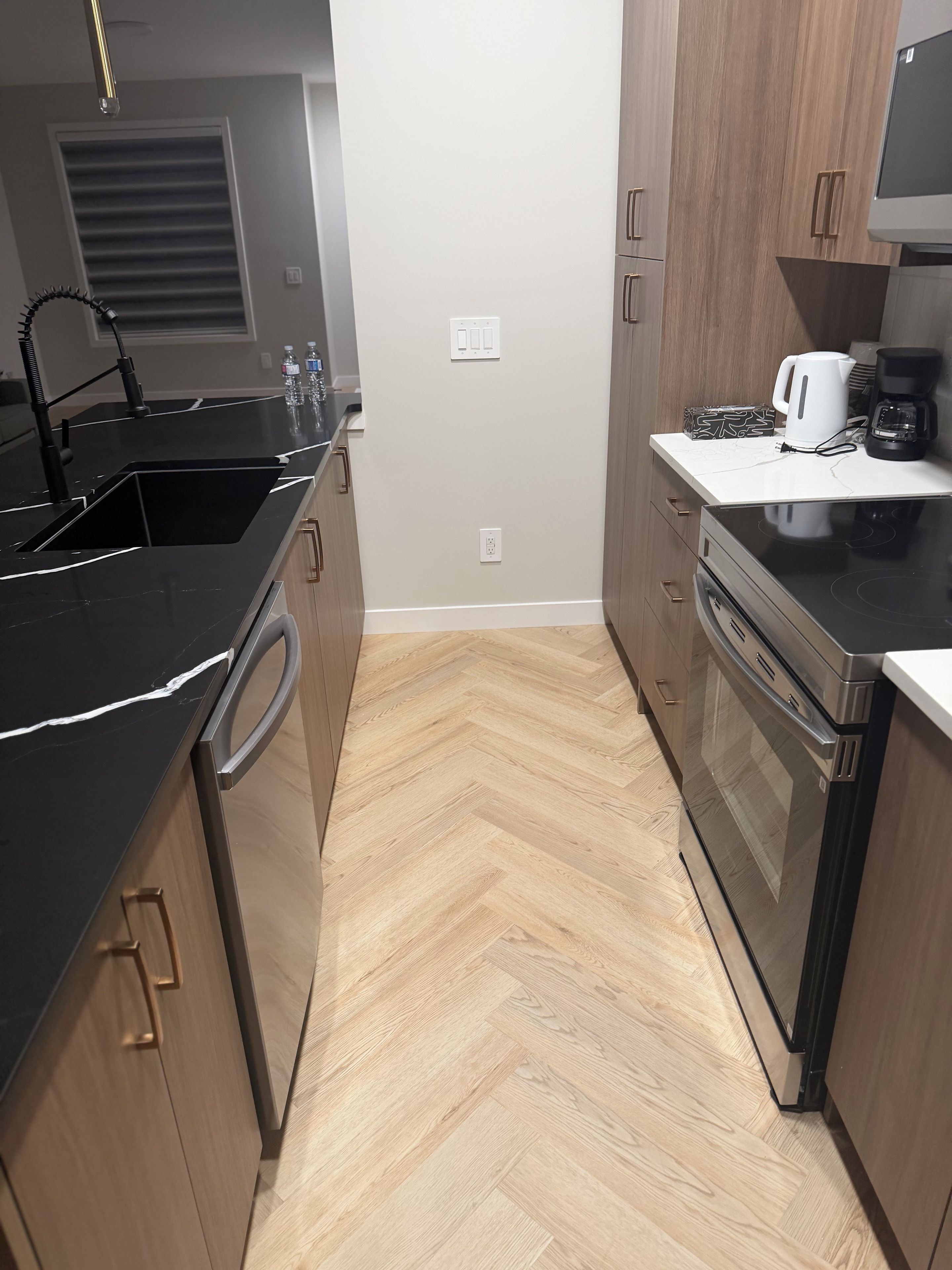 A kitchen with a black countertop, stainless steel appliances, and wooden cabinets.