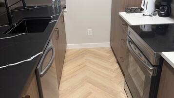 A kitchen with a black countertop, stainless steel appliances, and wooden cabinets.