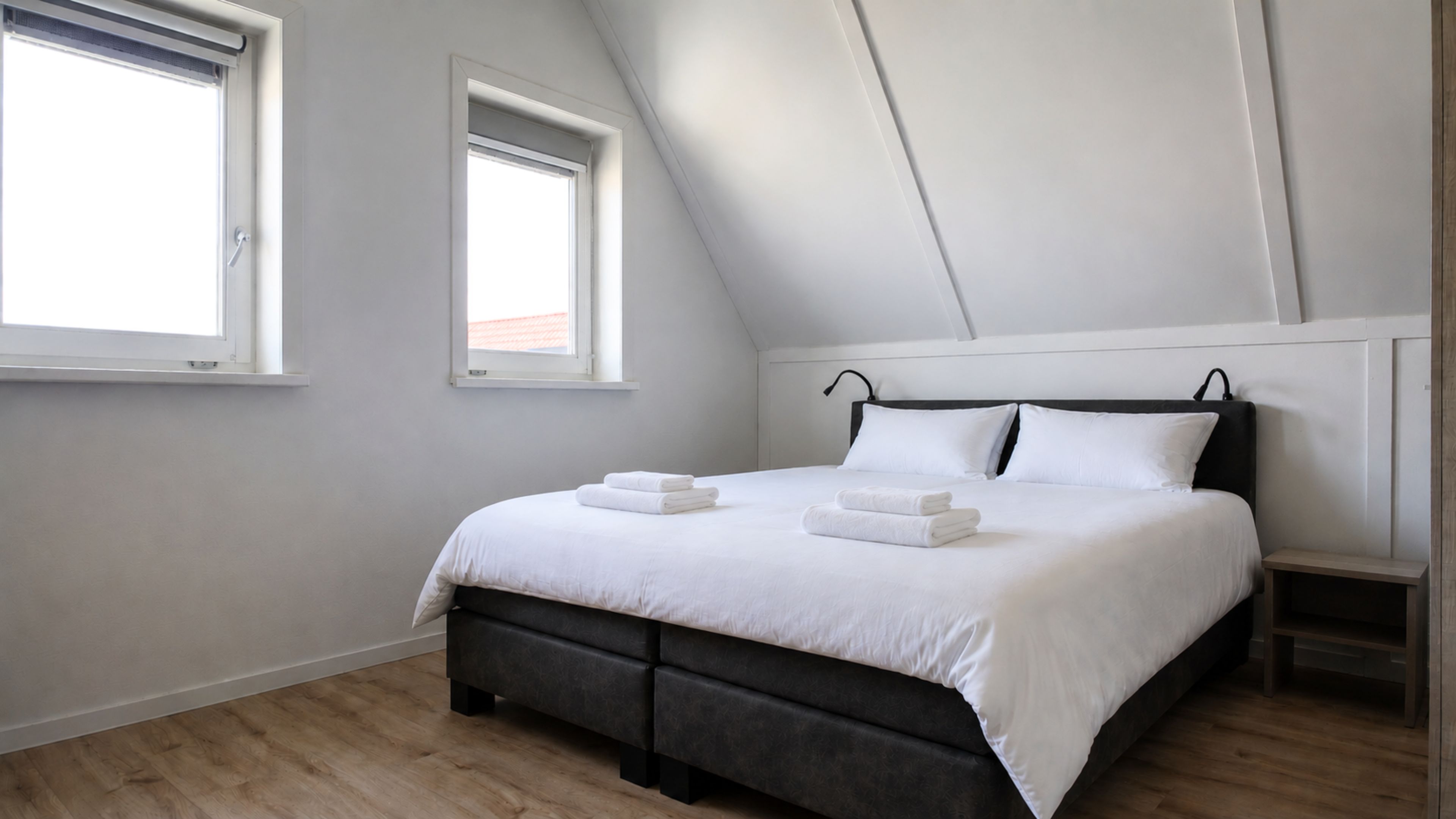 Una camera da letto con un letto, due comodini e due finestre.