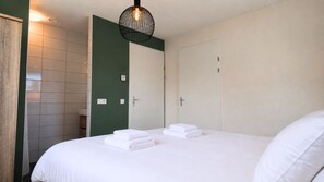 Ein Hotelzimmer mit einem Bett, zwei Türen, einer Duschkabine und einer Hängeleuchte.