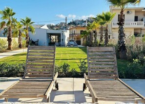 Two wooden lounge chairs facing a well-maintained lawn with a building in the background. - The Palms Seaside - Kolymvari (Kolymvari)