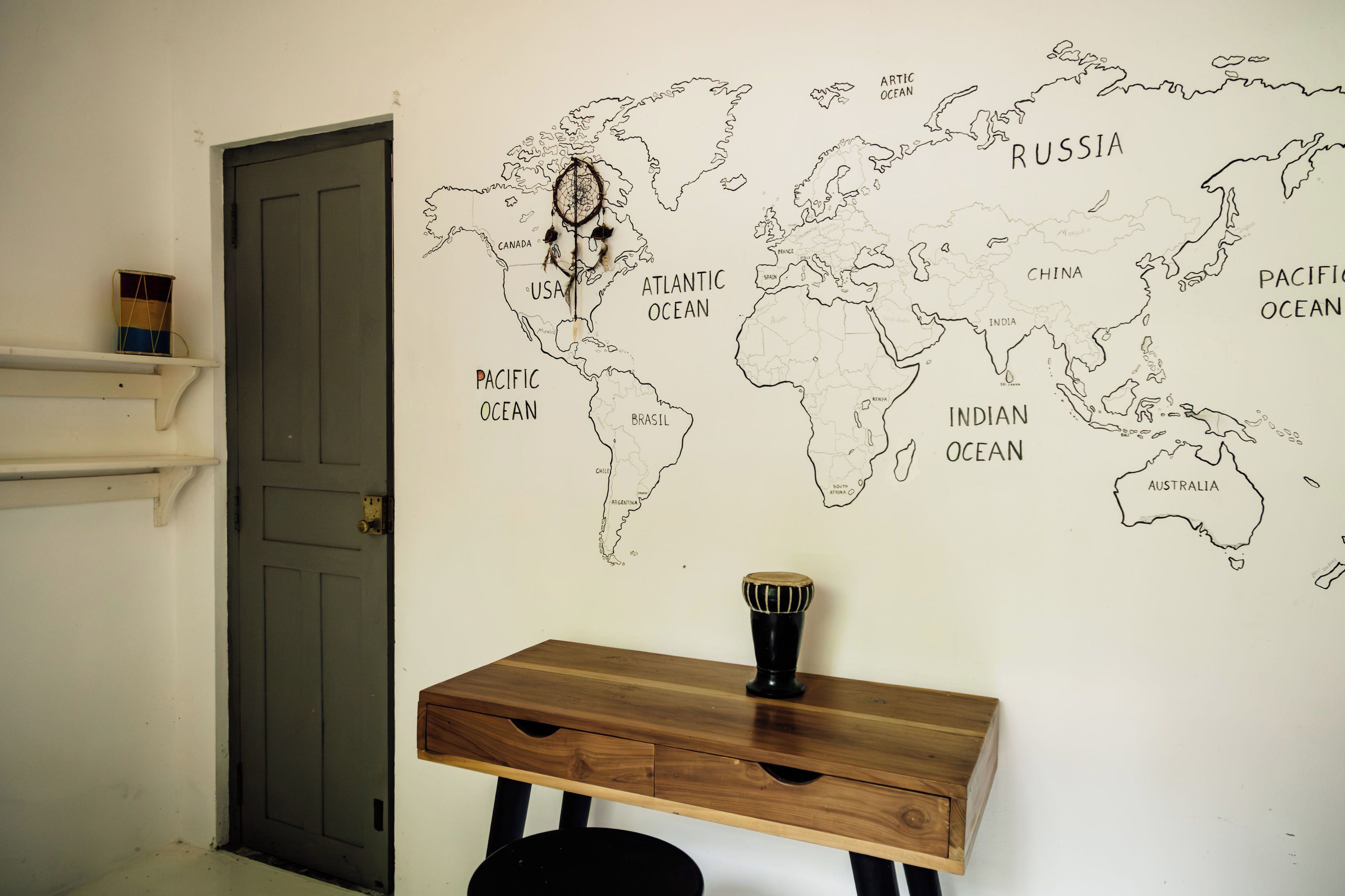 A room with a world map on the wall, a wooden desk, and a door.