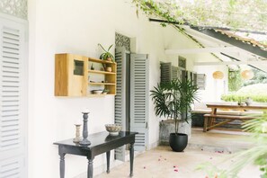 A room with a wooden cabinet, a black table, and a potted plant. - Oba Samaga by TONIK (Unawatuna)