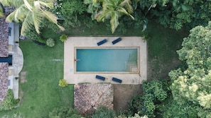 An aerial view of a rectangular swimming pool with two lounge chairs, surrounded by a grassy area and dense foliage. - Oba Samaga by TONIK (Unawatuna)