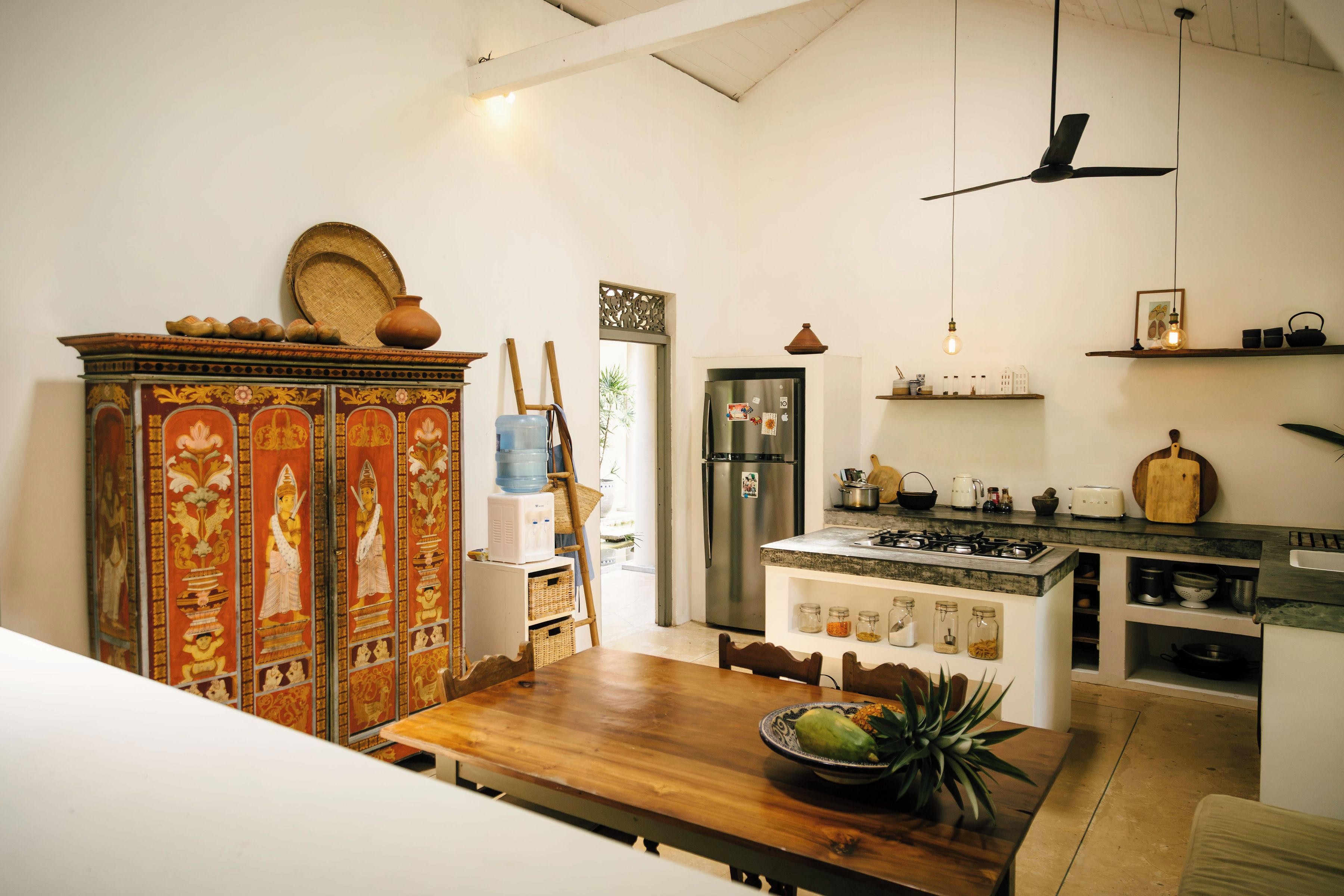 A kitchen with a stove, refrigerator, and a dining area with a table and chairs.