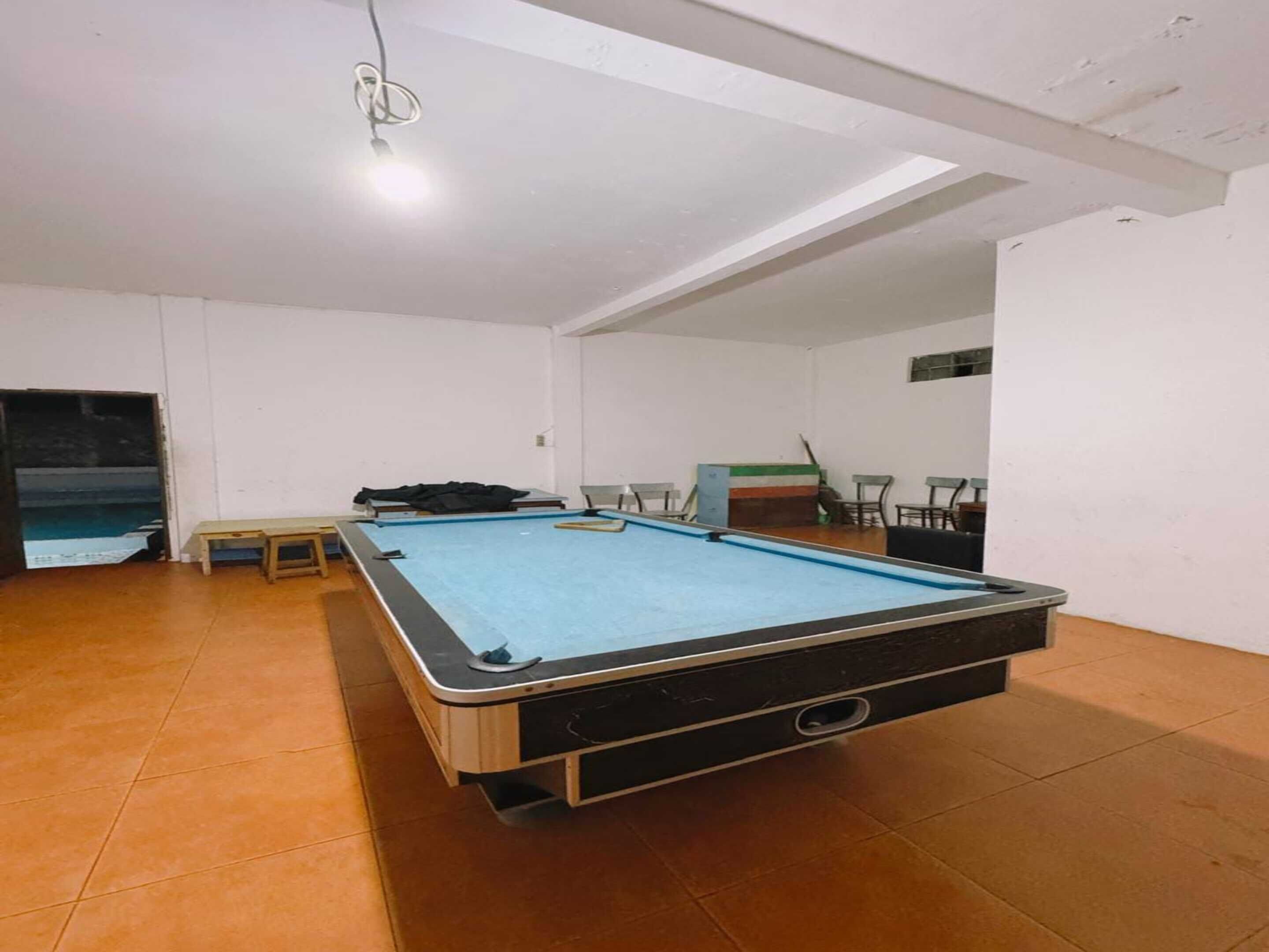 Una mesa de billar en una habitación con paredes blancas y suelo de baldosas.
