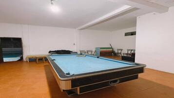 Una mesa de billar en una habitación con paredes blancas y suelo de baldosas.