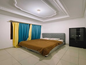 A bedroom with a bed, curtains, a wardrobe, and a ceiling with a light fixture. - Cozzy Villa Puri (BOGOR)
