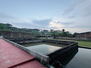 Una fuente de agua con una estructura de concreto, un pequeño edificio y un muro de piedra.