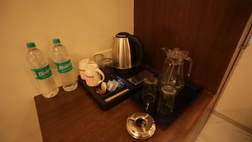 A kitchenette area with a coffee maker, two Bisleri water bottles, a mug, and a tray with utensils.