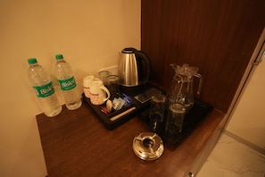 A kitchenette area with a coffee maker, two Bisleri water bottles, a mug, and a tray with utensils. - HOTEL ROYAL STAY (Nagpur)
