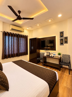 A hotel room with a bed, a desk, a chair, a television, and an air conditioning unit. - HOTEL ROYAL STAY (Nagpur)