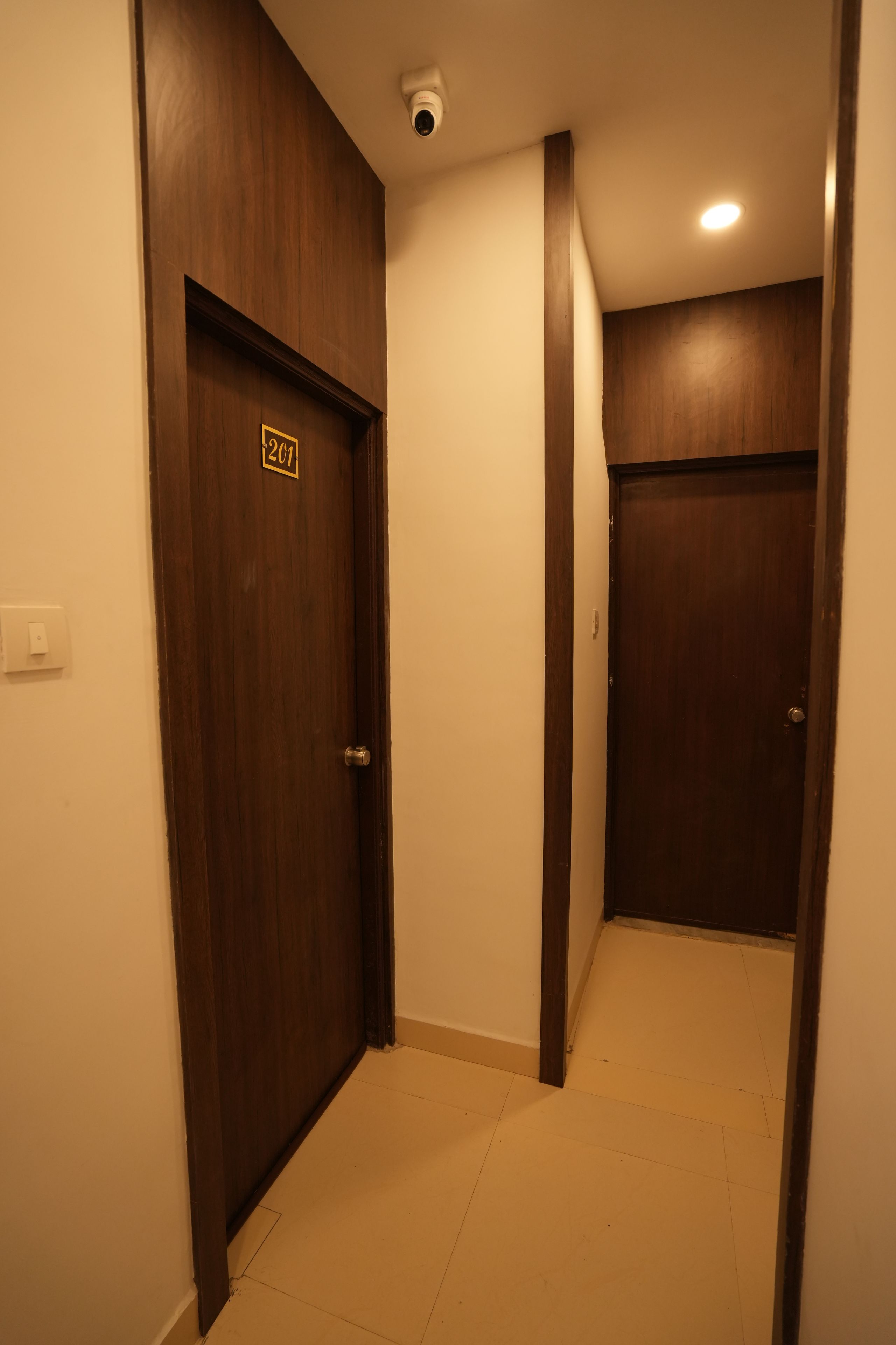 A hallway with two wooden doors, one marked with the number 201.