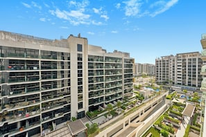 A modern multi-story building with a glass facade, outdoor seating areas, and a pool. - Bloomfields Studio in Azizi Riviera 43 (Dubai)