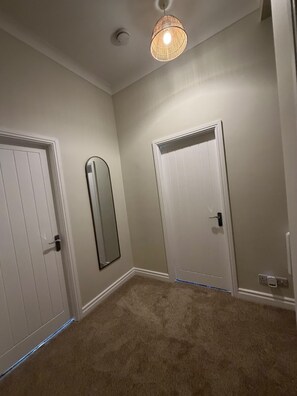 A room with two white doors, a hanging light fixture, and a carpeted floor. - Free On-site Parking - Central - WIFI - Grd Floor (Darlington)