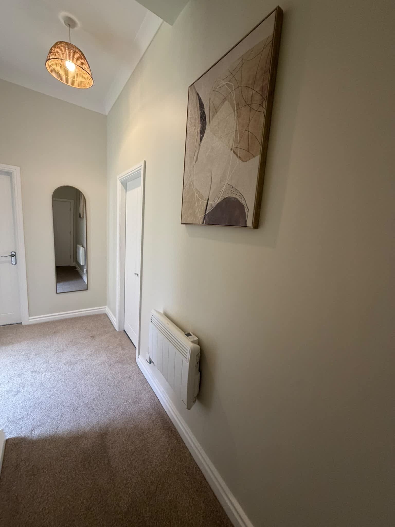 Un couloir avec un radiateur, une porte et un luminaire suspendu.