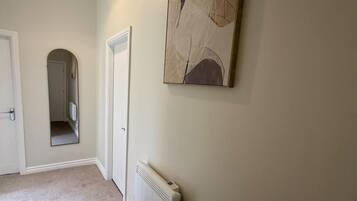 Un couloir avec un radiateur, une porte et un luminaire suspendu.