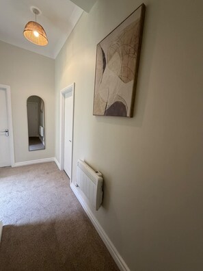 A hallway with a radiator, a door, and a hanging light fixture. - Free On-site Parking - Central - WIFI - Grd Floor (Darlington)