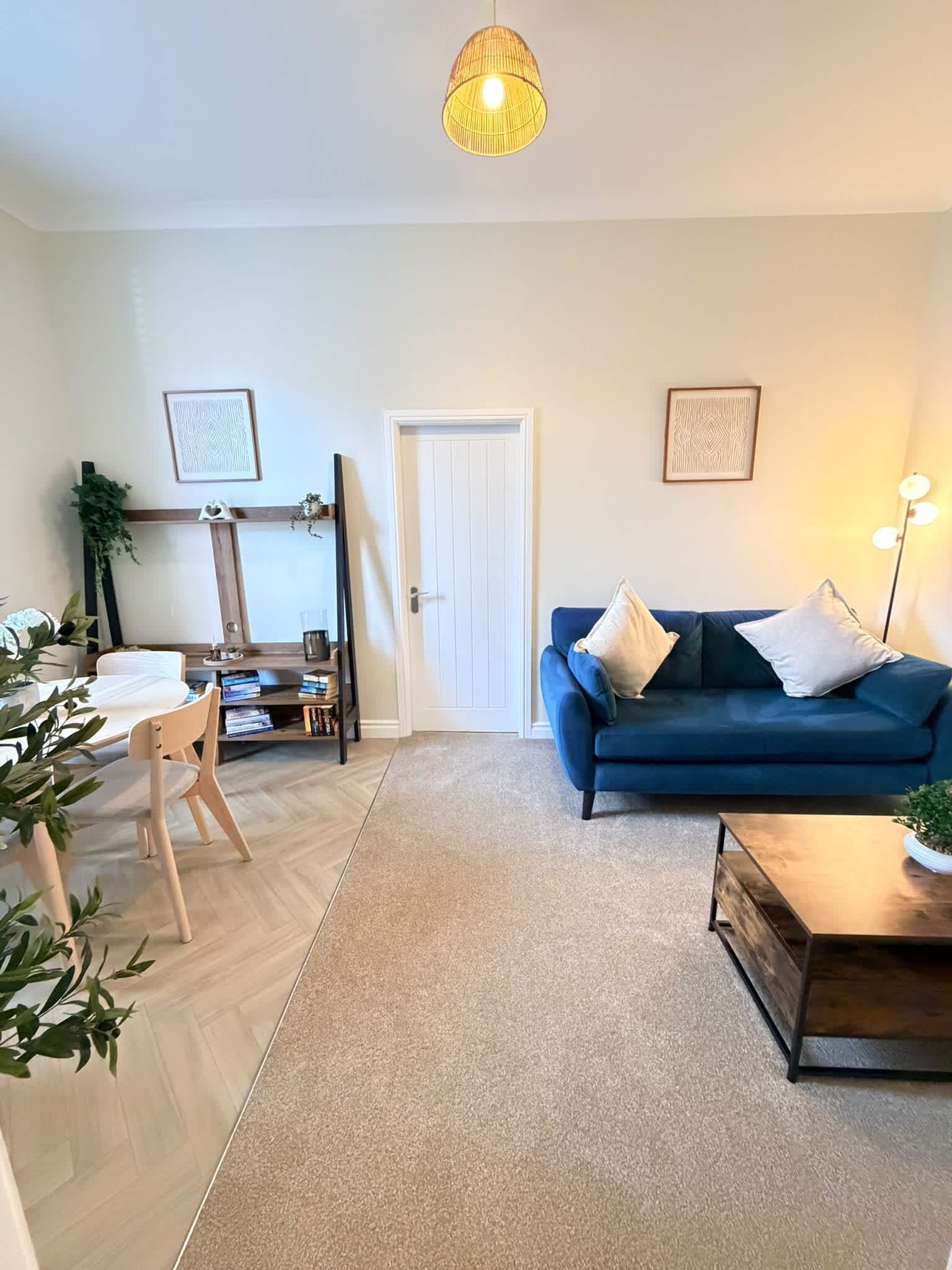 A living room with a blue sofa, a coffee table, a bookshelf, and a door.