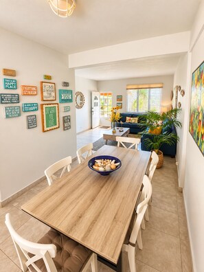 Een eetruimte met een houten tafel, witte stoelen en een schaal met snacks.