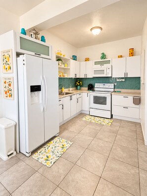 A kitchen with white cabinets, a refrigerator, a microwave, an oven, and a sink. - Ramey Base 3BR/2BA / Surf + Solar + Starlink + AC (Aguadilla)