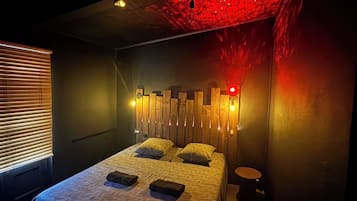 A bedroom with a bed, bedside tables, and a wall-mounted light fixture.