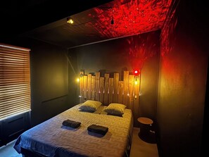 A bedroom with a bed, bedside tables, and a wall-mounted light fixture. - defaultName (Lacroix-Falgarde)