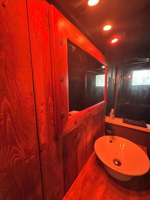 A wooden bathroom with a single sink and a mirror.