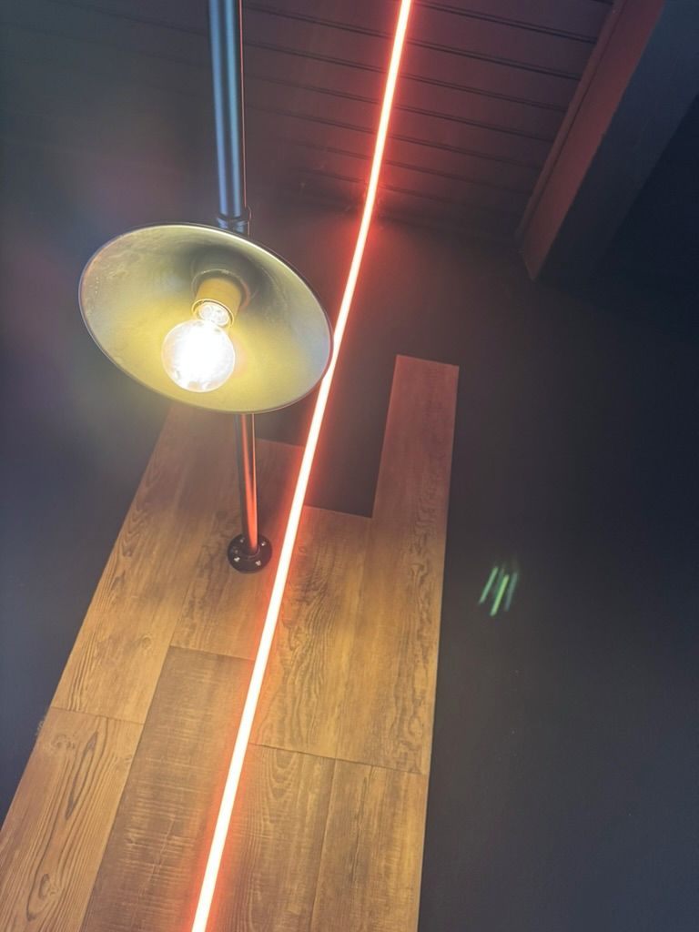 Een lamp met een zichtbare gloeilamp en een houten vloer.