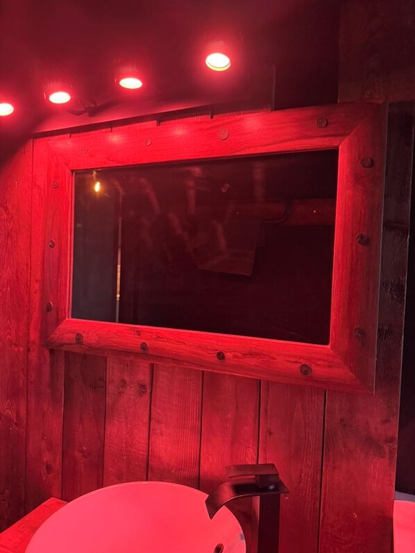 A wooden-framed window with a red tint, a white chair, and a small table.