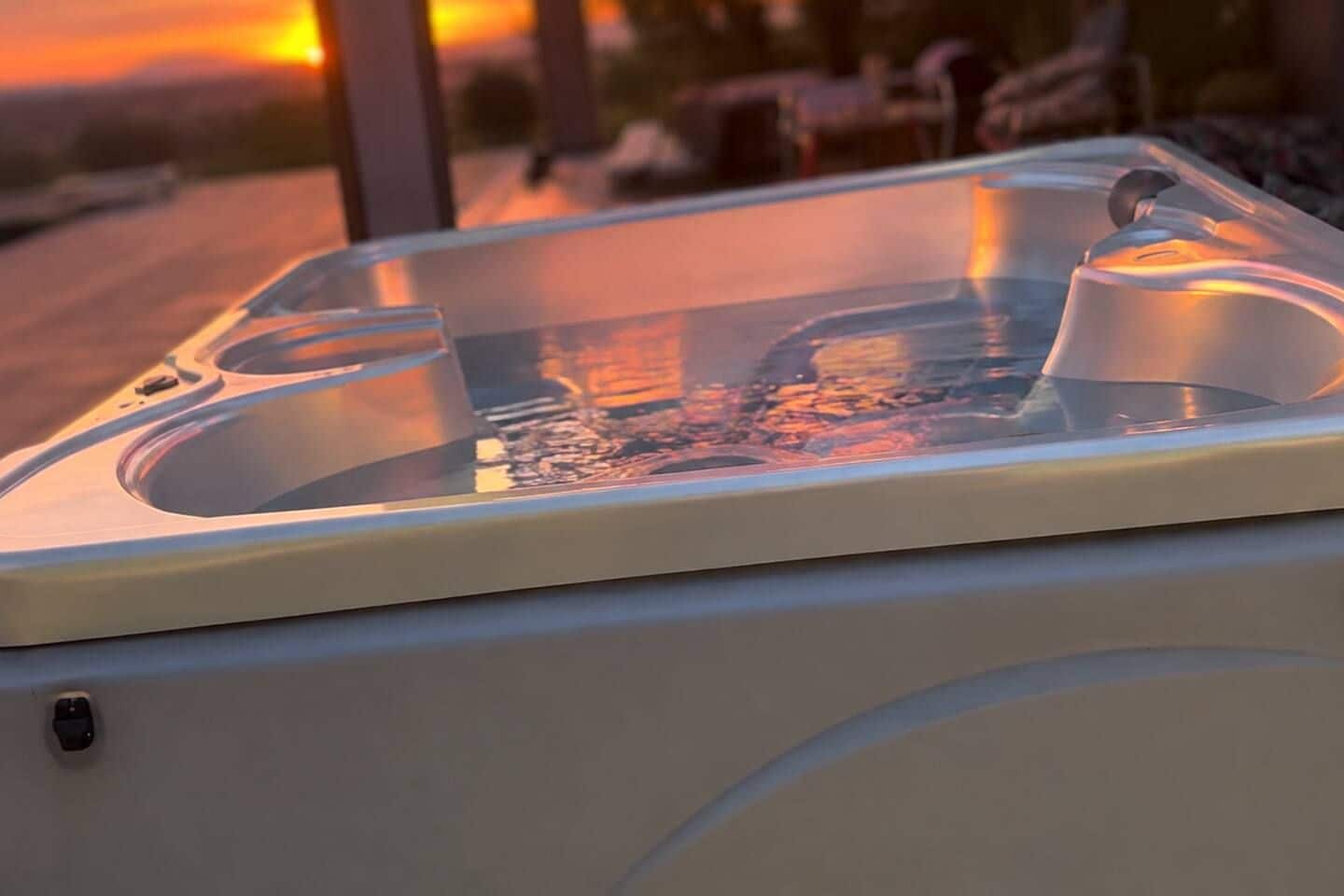 Lämminvesiallas, jonka päällä on läpinäkyvä lasikansi, ja taustalla auringonlaskunäkymä.