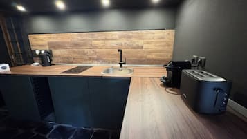 Une cuisine moderne dotée d’un plan de travail en bois, d’un évier, d’une machine à café et d’un grille-pain.