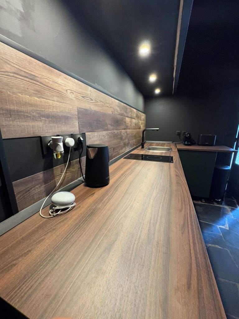 A modern kitchen with a wooden countertop, a coffee machine, and a built-in oven.