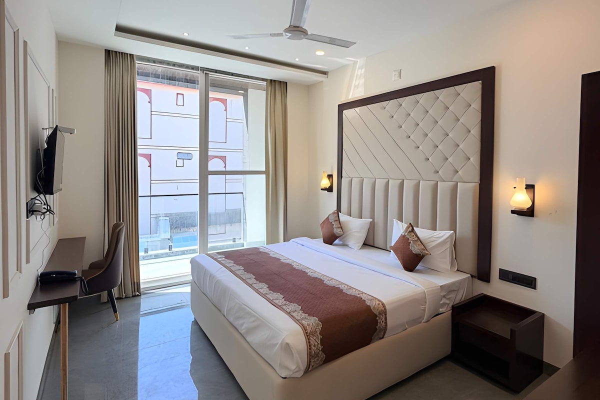 Habitación de hotel moderna con una cama grande, un escritorio, una silla y vistas al exterior.