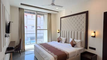A modern hotel room with a large bed, a desk, a chair, and a view of the outside.
