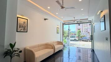 A modern lobby with a sofa, ceiling fan, and framed artwork.